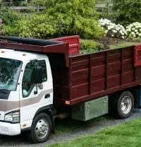 White and red dump truck parked on grass in a landscaped yard