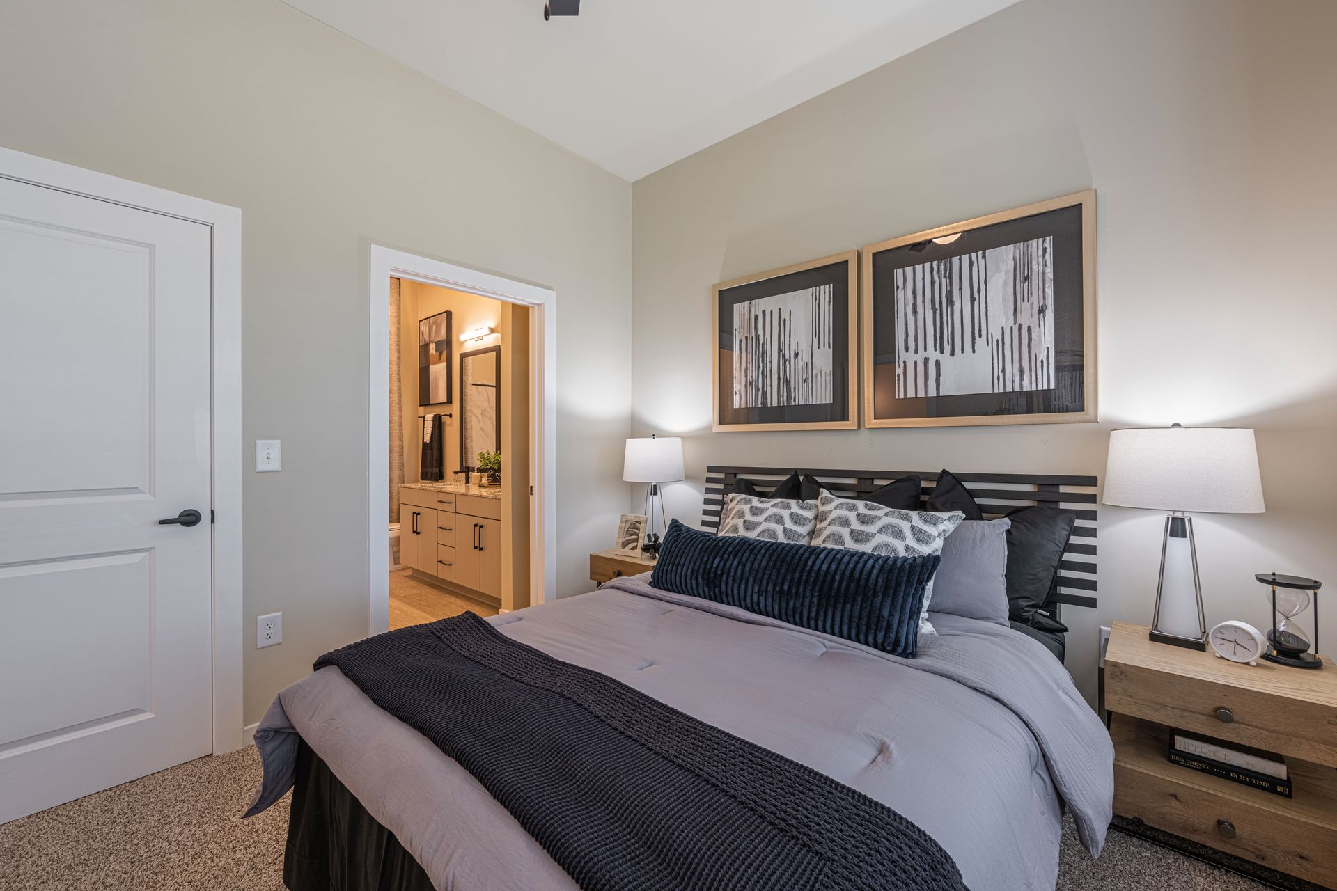 Bedroom with bed, nightstands, artwork, and open door to a bathroom.