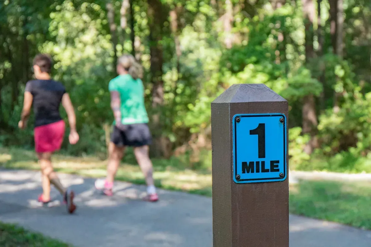 A wooden post with a blue sign that says `` 1 mile '' on it.