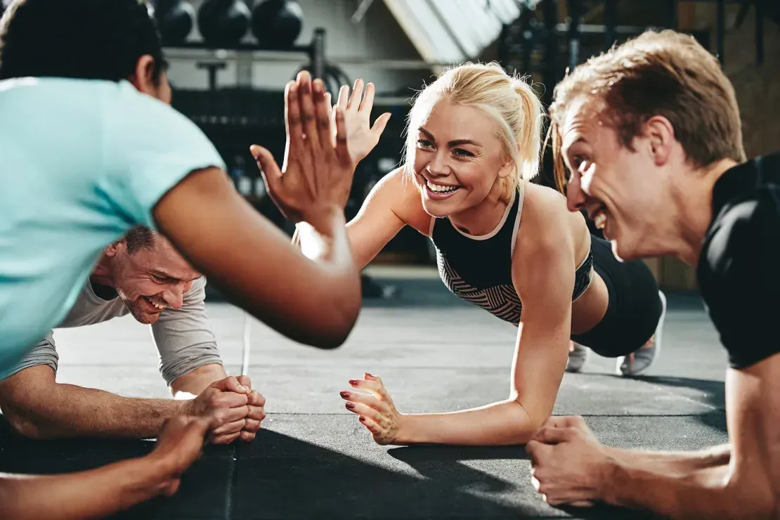 A group of people are doing push ups together in a gym and giving each other a high five.