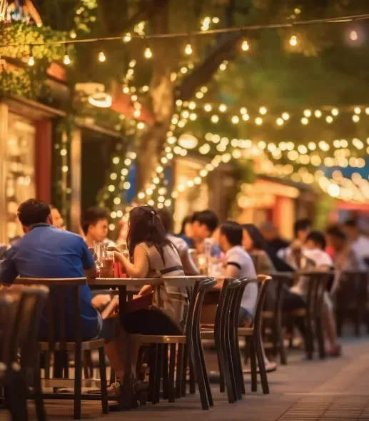 A group of people are sitting at tables outside a restaurant.