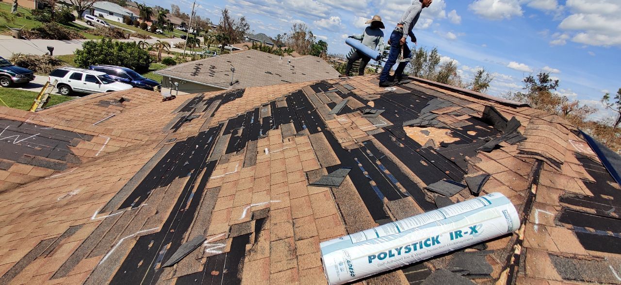 Roof under construction with black underlayment and a worker on top in a sunny rural area