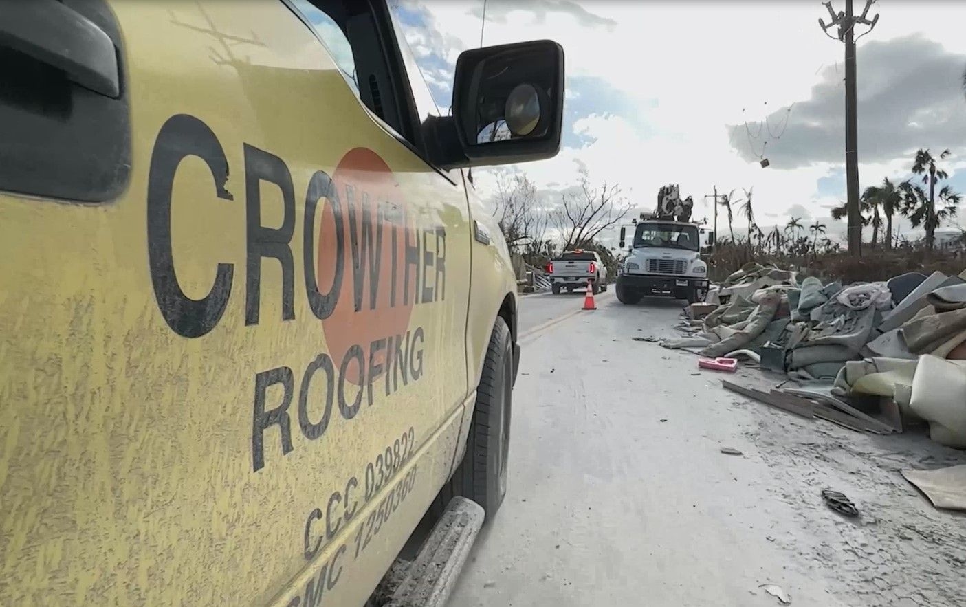 Yellow van on a debris-strewn street, with rubble and damaged buildings in the background under a cloudy sky