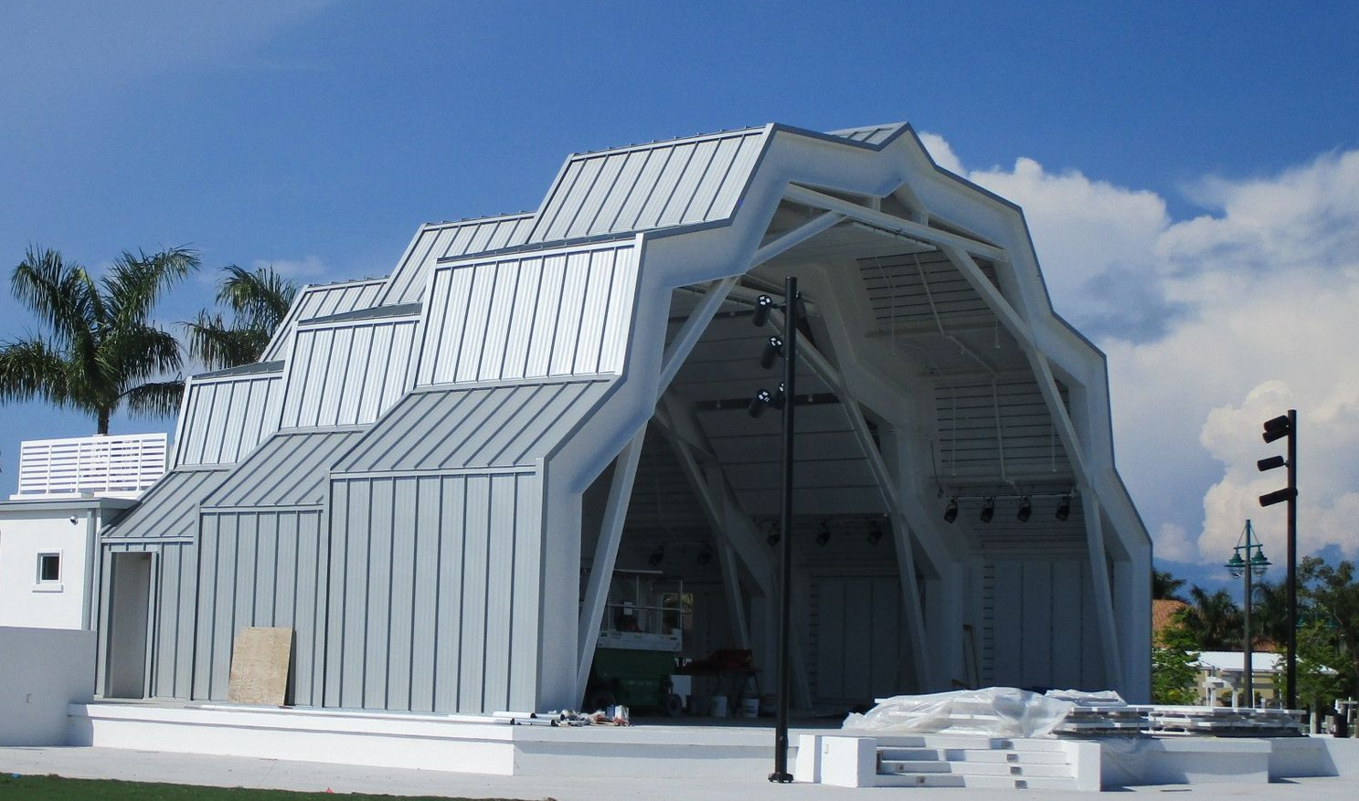 Modern white geometric building with a peaked roof under a blue sky