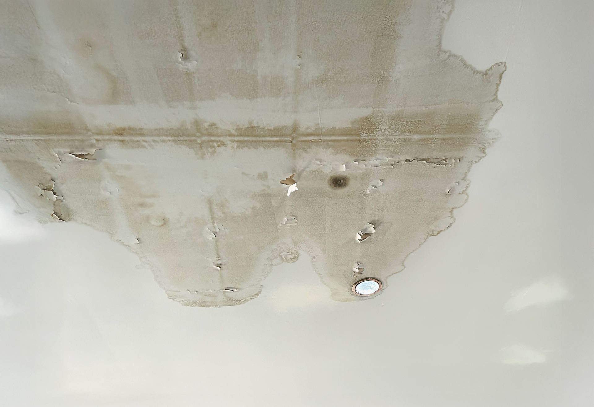 Water-stained ceiling with peeling paint and several ceiling light fixtures
