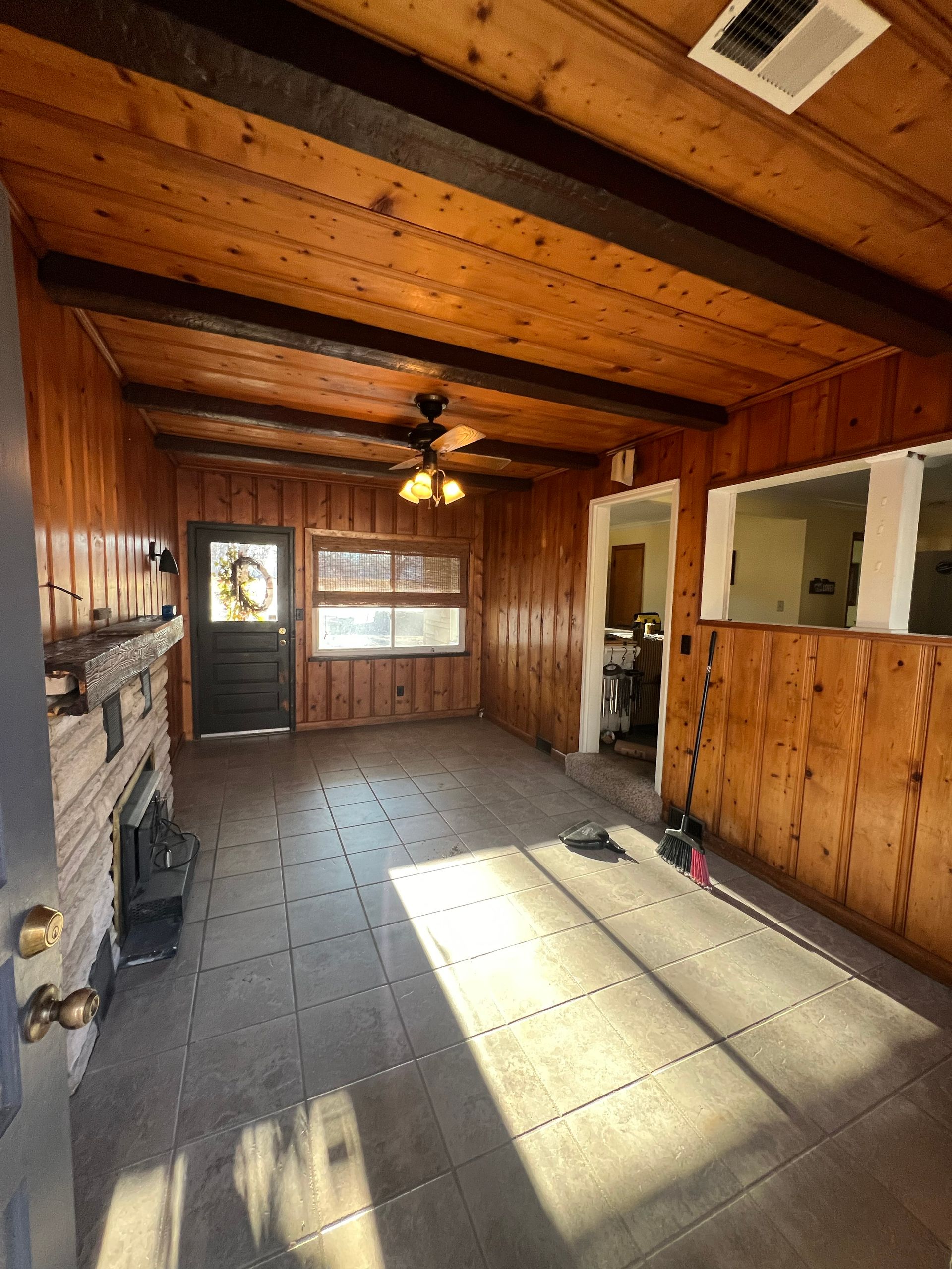 Living room with wood paneling, a fireplace, and a door leading outside.