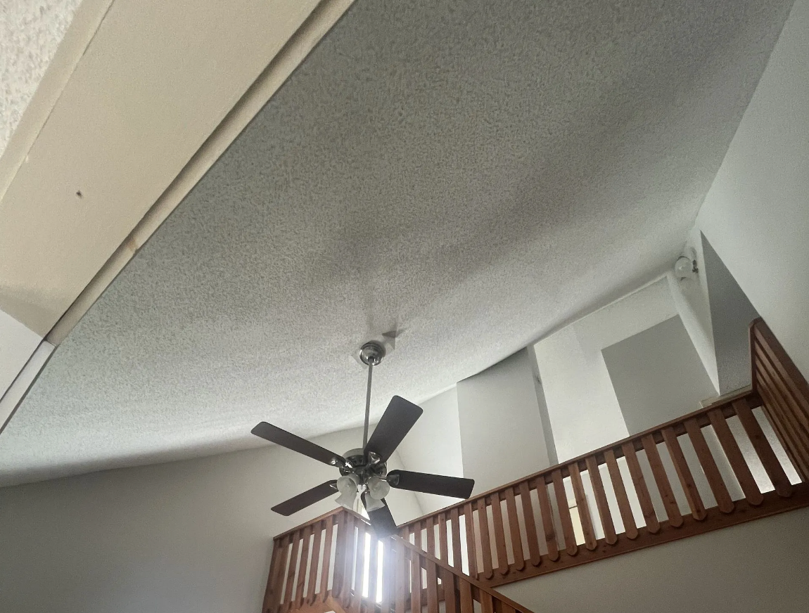 Ceiling fan in a high-ceilinged room with a loft overlooking a stairwell.