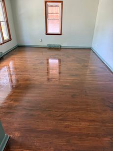 Room with polished, dark wood floors, light green walls, and a small window reflecting light.