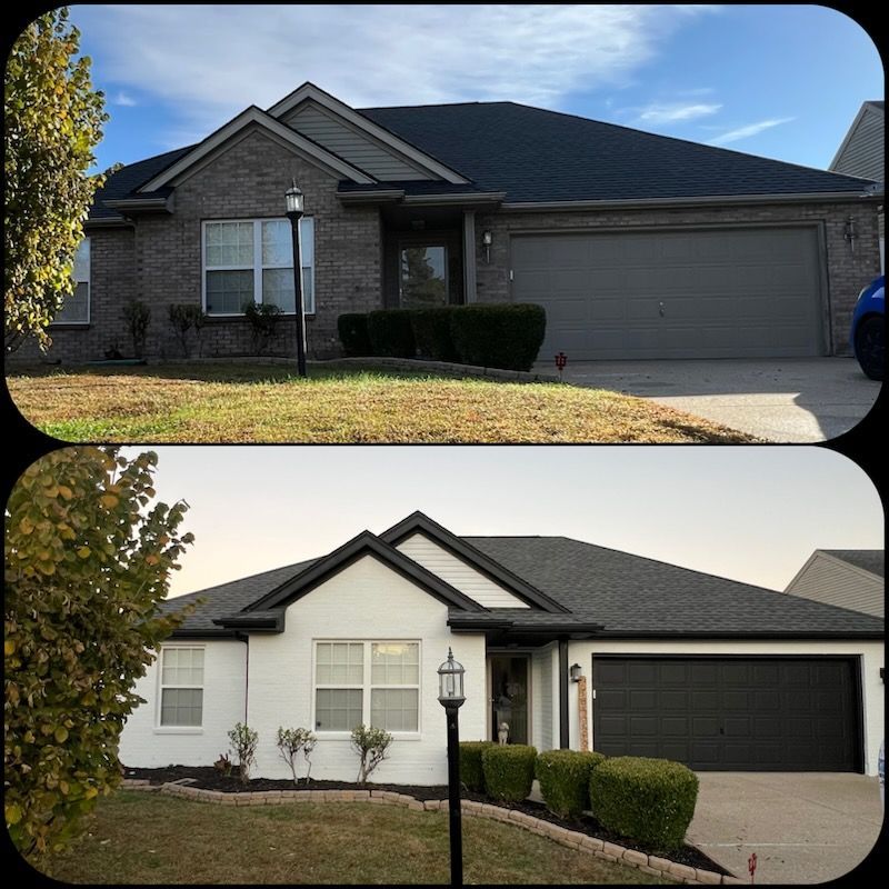 House exterior with brick, light blue, and black accents.  Two windows visible, bushes in front of the building.
