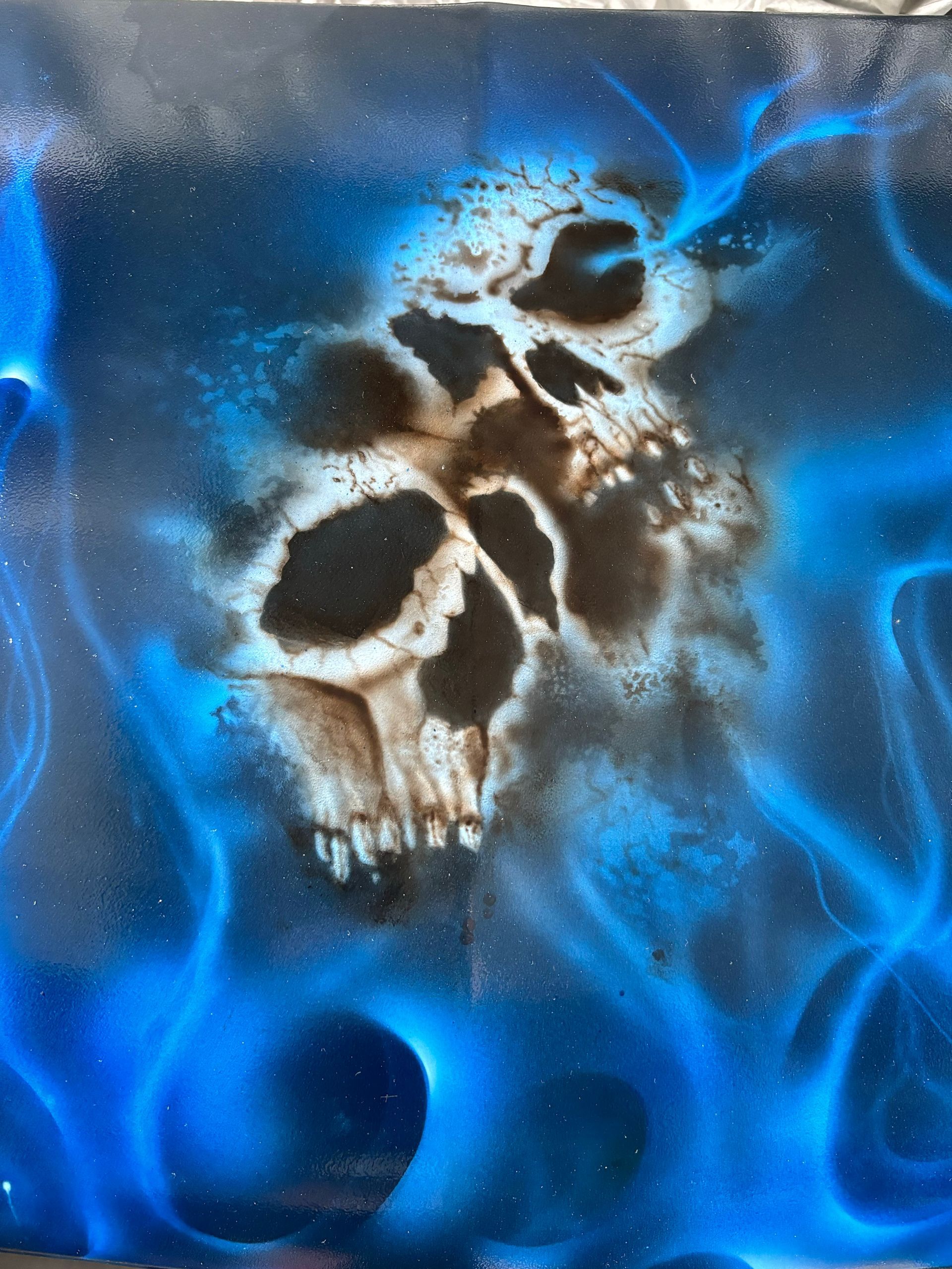 Twee schedels die oprijzen uit blauwe rook tegen een donkere achtergrond.