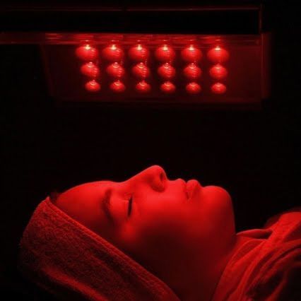 Une femme est allongée sous une lumière rouge, les yeux fermés.