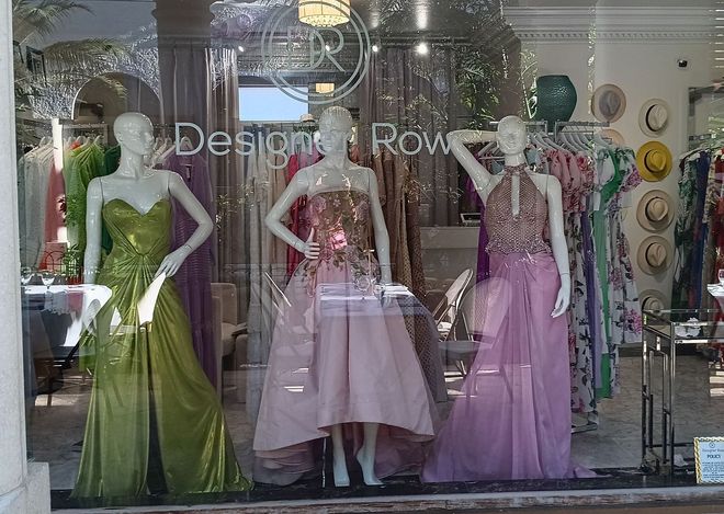A window display of dresses on mannequins in a store.