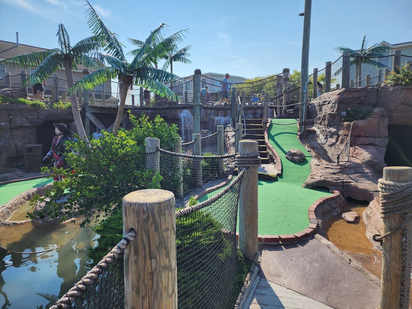 A woman is standing on a mini golf course holding a golf club.