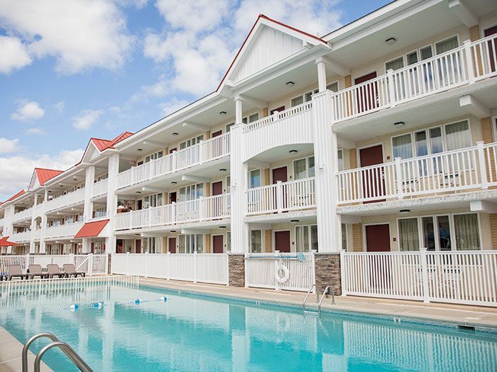 A large hotel with a swimming pool in front of it.