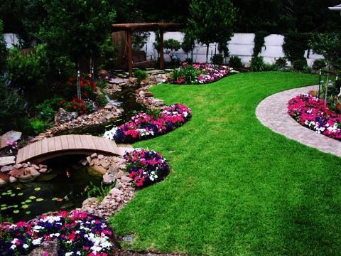 A garden with flowers and a bridge over a pond