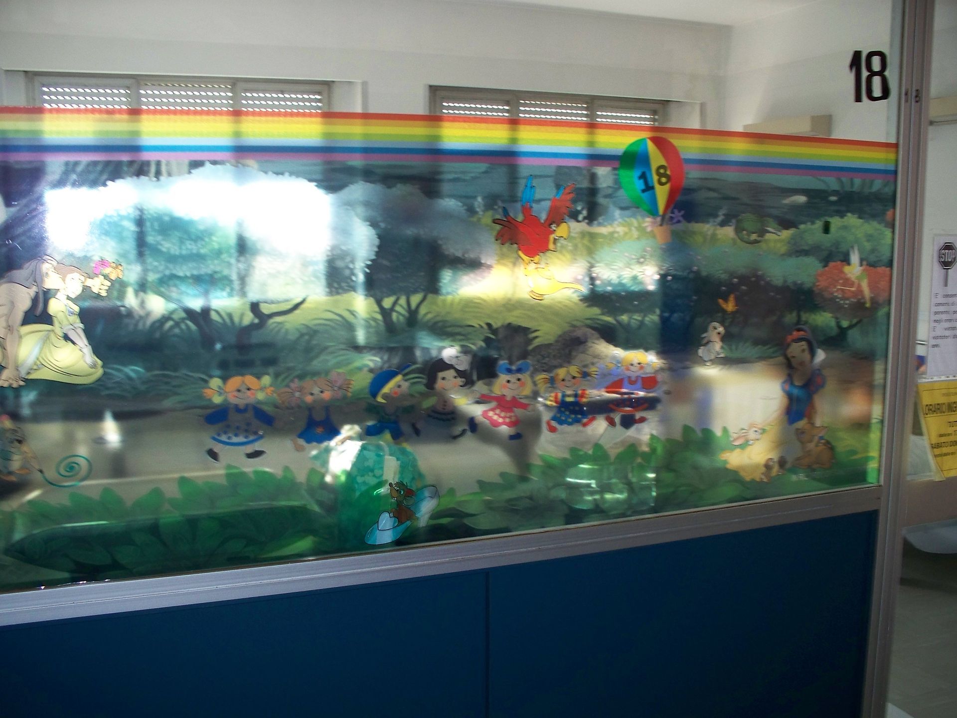 Scena colorata dipinta con personaggi dei cartoni animati, tra cui Biancaneve, su uno sfondo arcobaleno, su una vetrata.