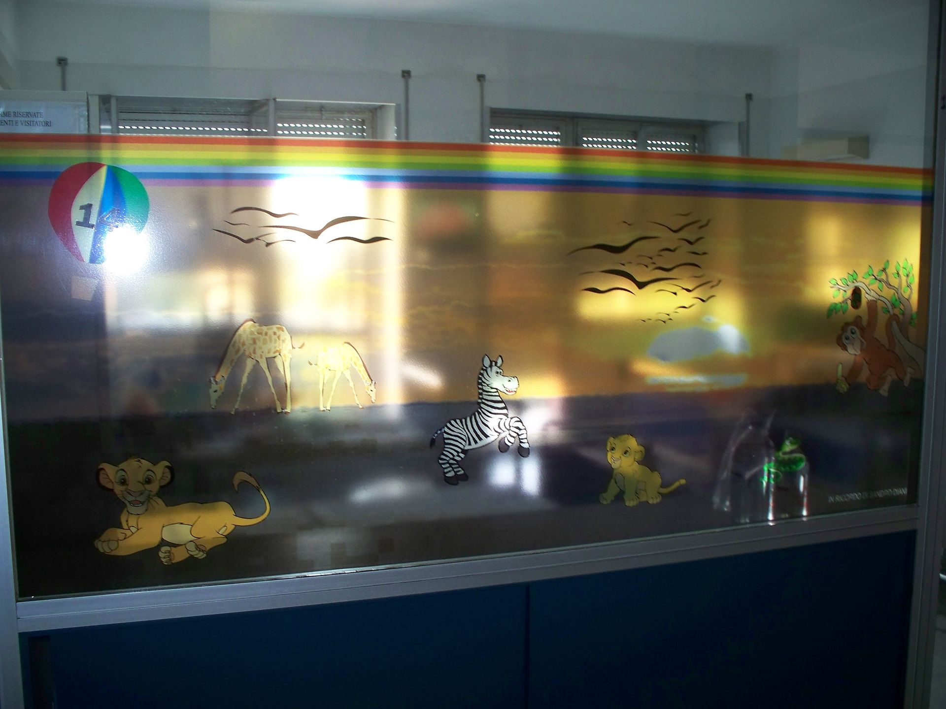 Finestra con arcobaleno, animali dei cartoni animati (cuccioli di leone, zebra), uccelli e una palla colorata.