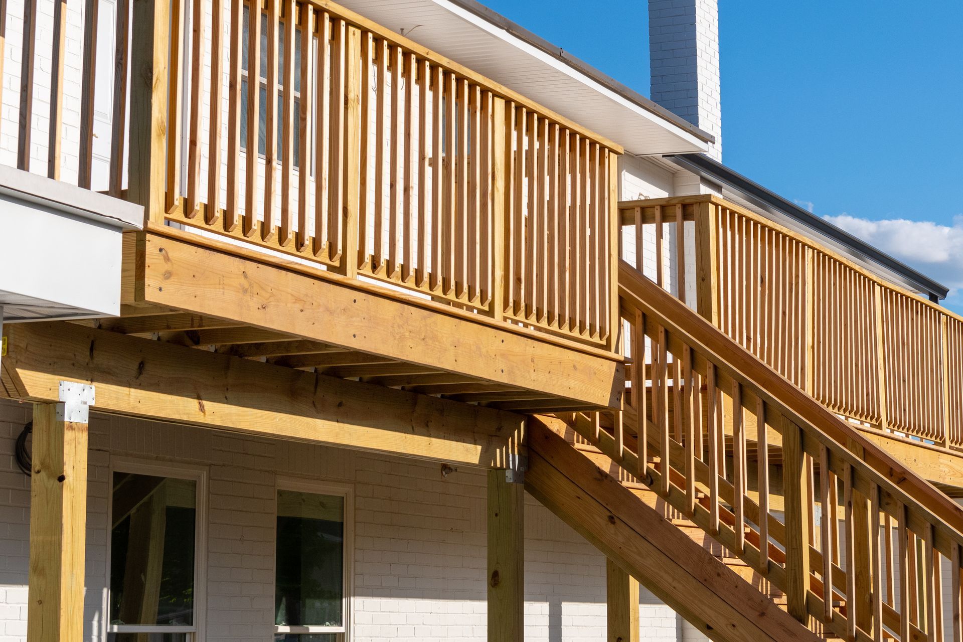 Wooden deck and staircase on the side of a house under a blue sky Wooden deck and staircase on the side of a house under a blue sky