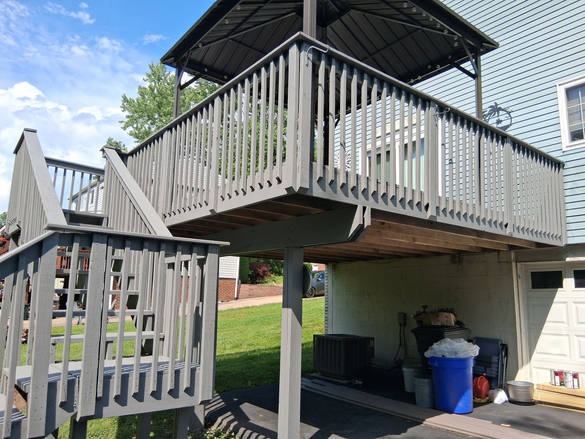 Elevated wooden deck with stairs and a covered seating area above a yard