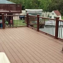 Wooden deck with brown railing overlooking a yard and neighboring houses