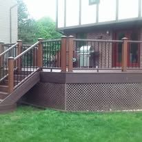 Back deck with wooden stairs, railing, and green lawn beside a house