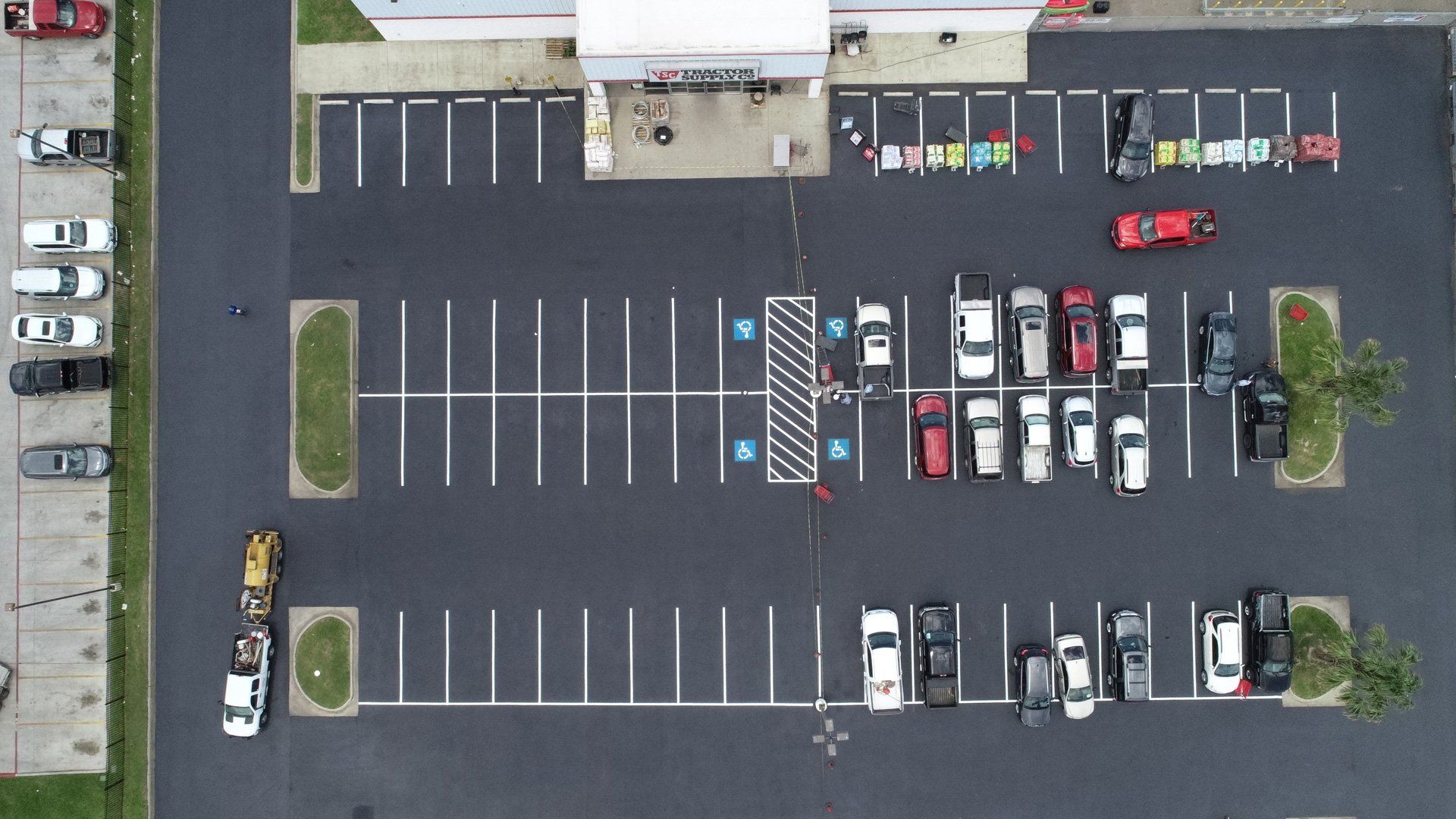 An aerial view of a parking lot with a store entrance, several parked cars, and marked accessible parking spaces.