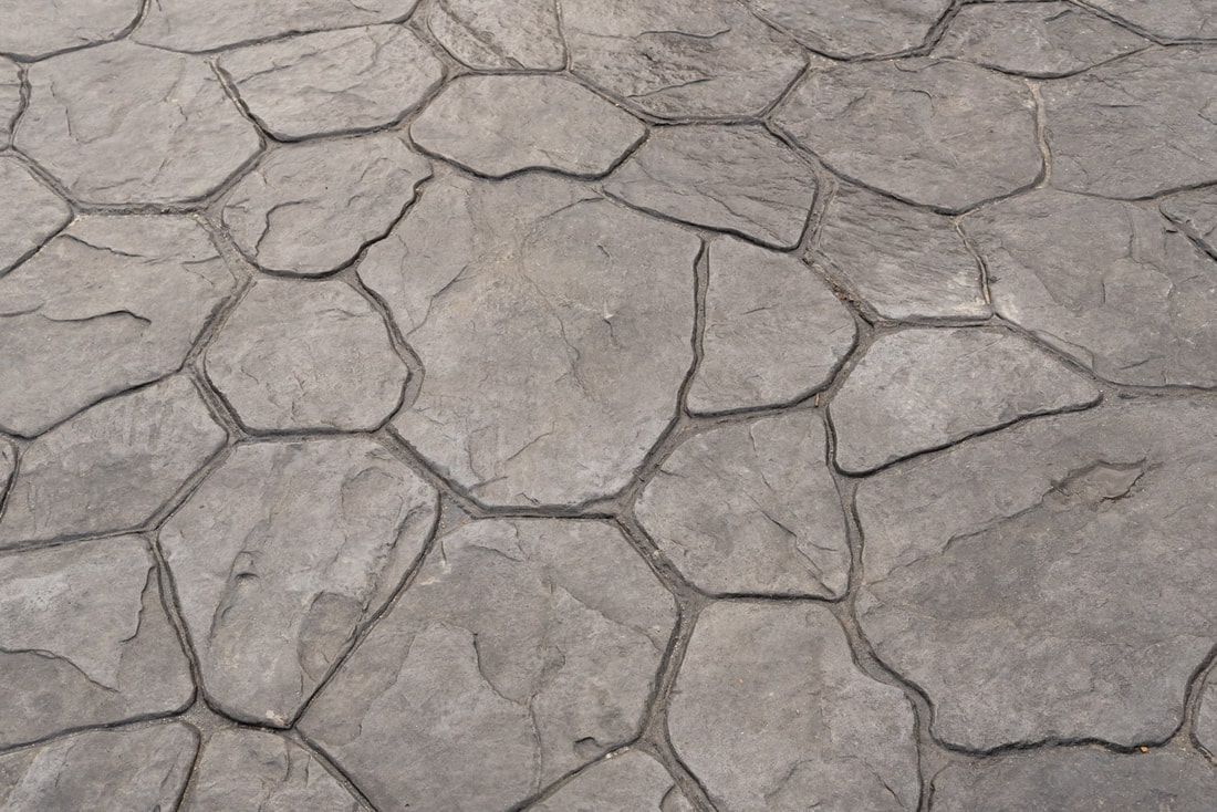 Roughly textured, irregular gray stone pavement with a natural, rustic appearance. 