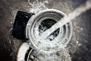 A can of soda is being splashed with water.