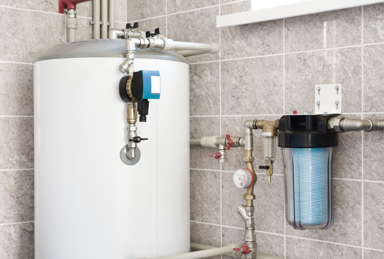A water heater is sitting in a bathroom next to a water filter.