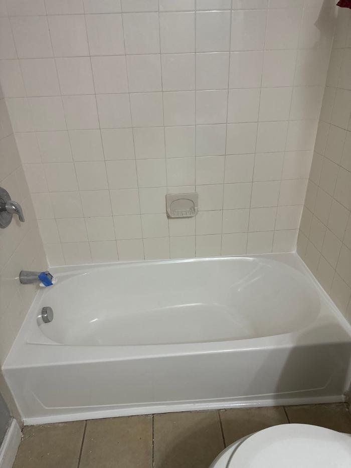 White bathtub in a tiled bathroom with a faucet and soap dish.