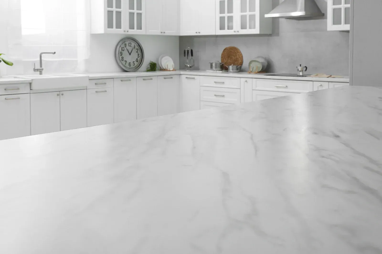 White kitchen with marble countertop, cabinets, clock, and sink.