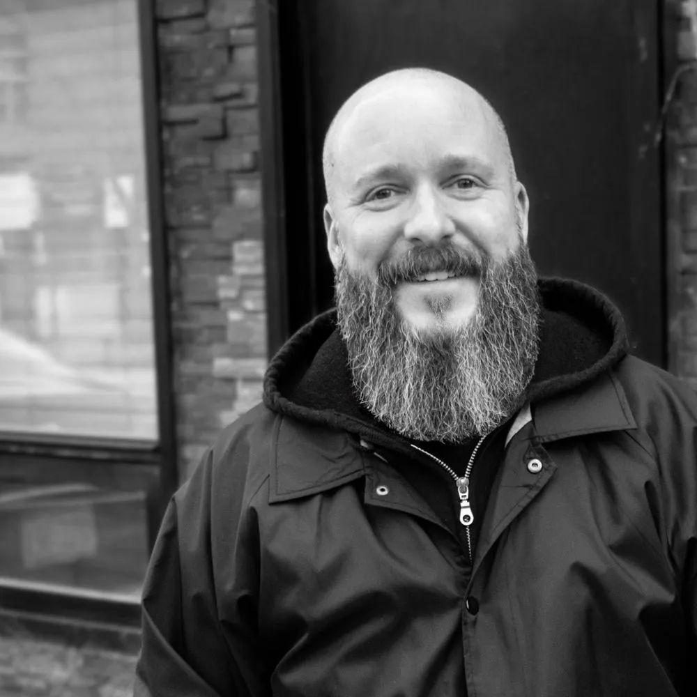 A bald man with a beard wearing a black jacket