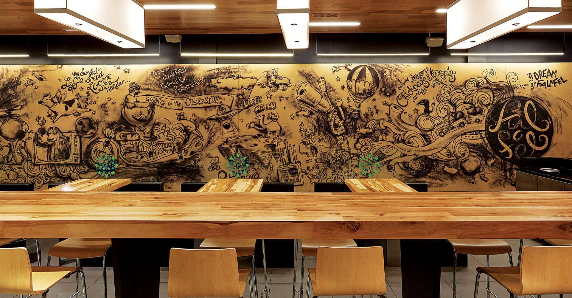 Modern restaurant interior with long wooden table, stools, and a patterned mural wall