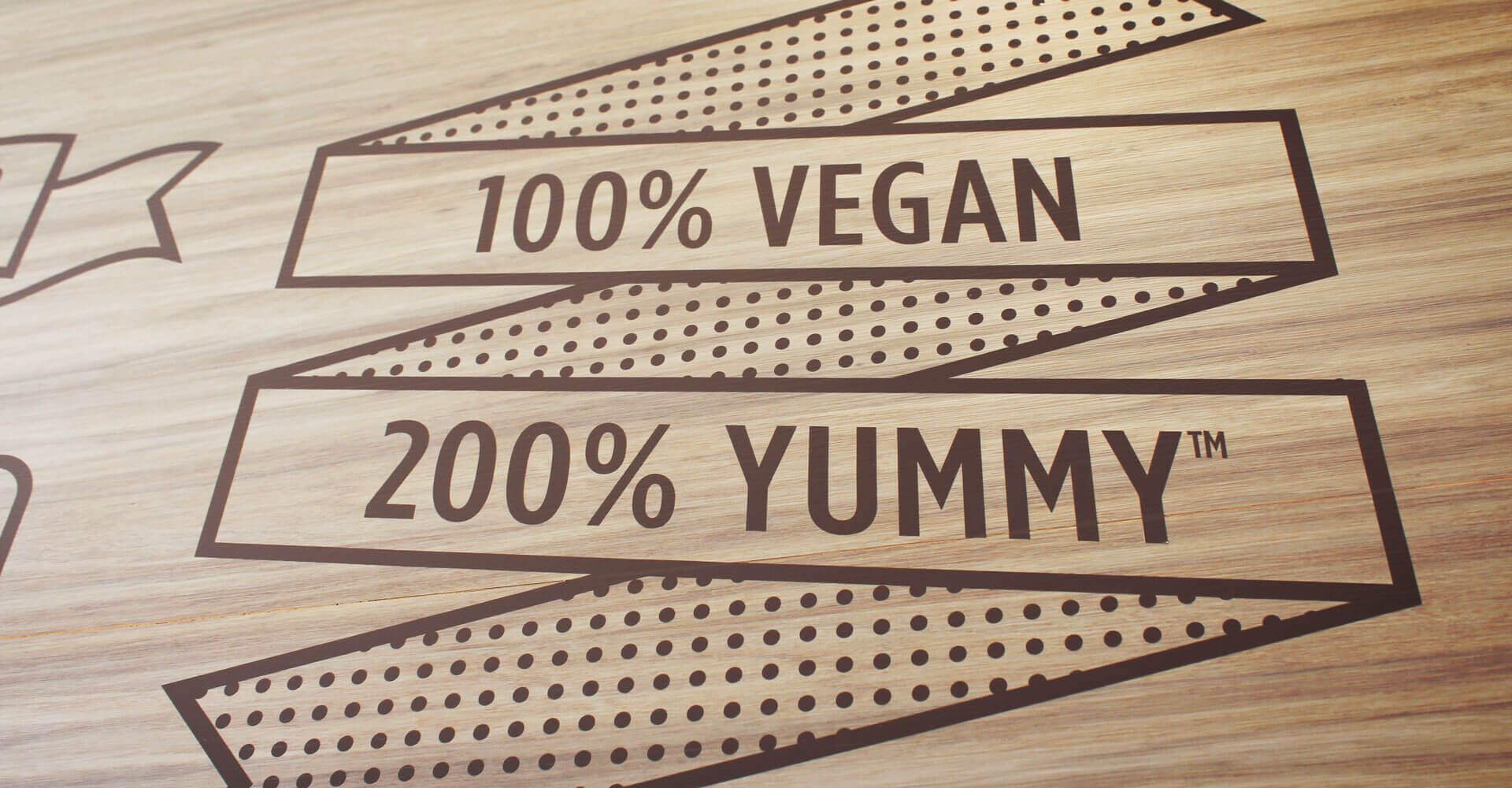 A wooden sign that says 100 % vegan and 200 % yummy