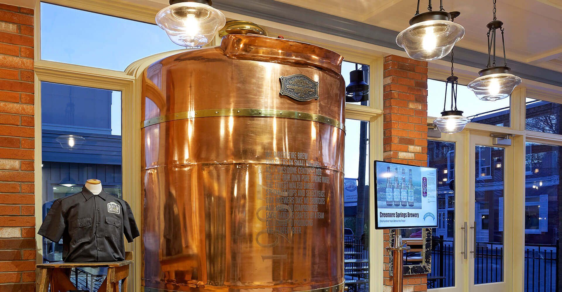 A large copper tank is sitting in a room next to a window.