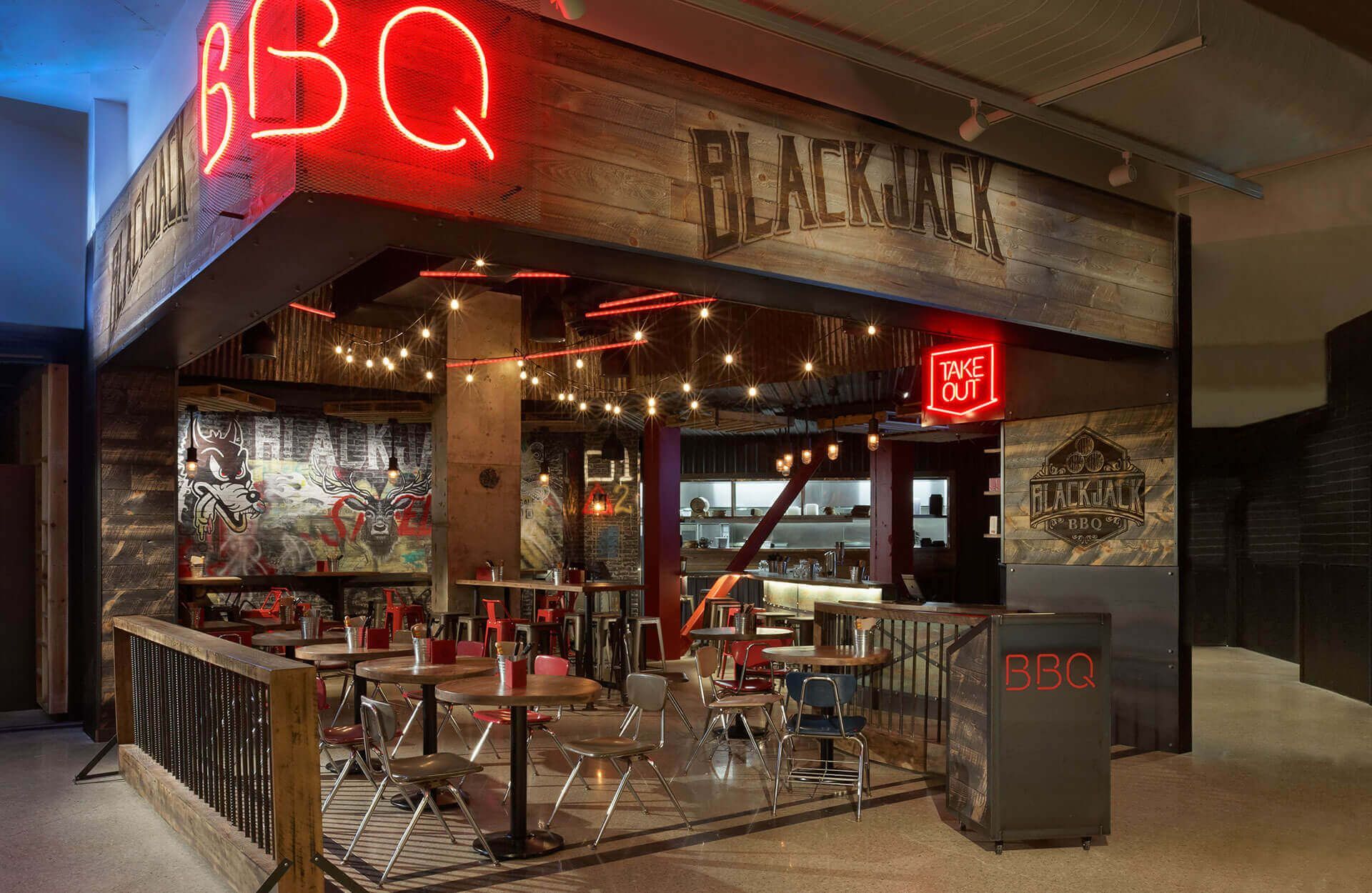 A restaurant with tables and chairs under a neon sign.