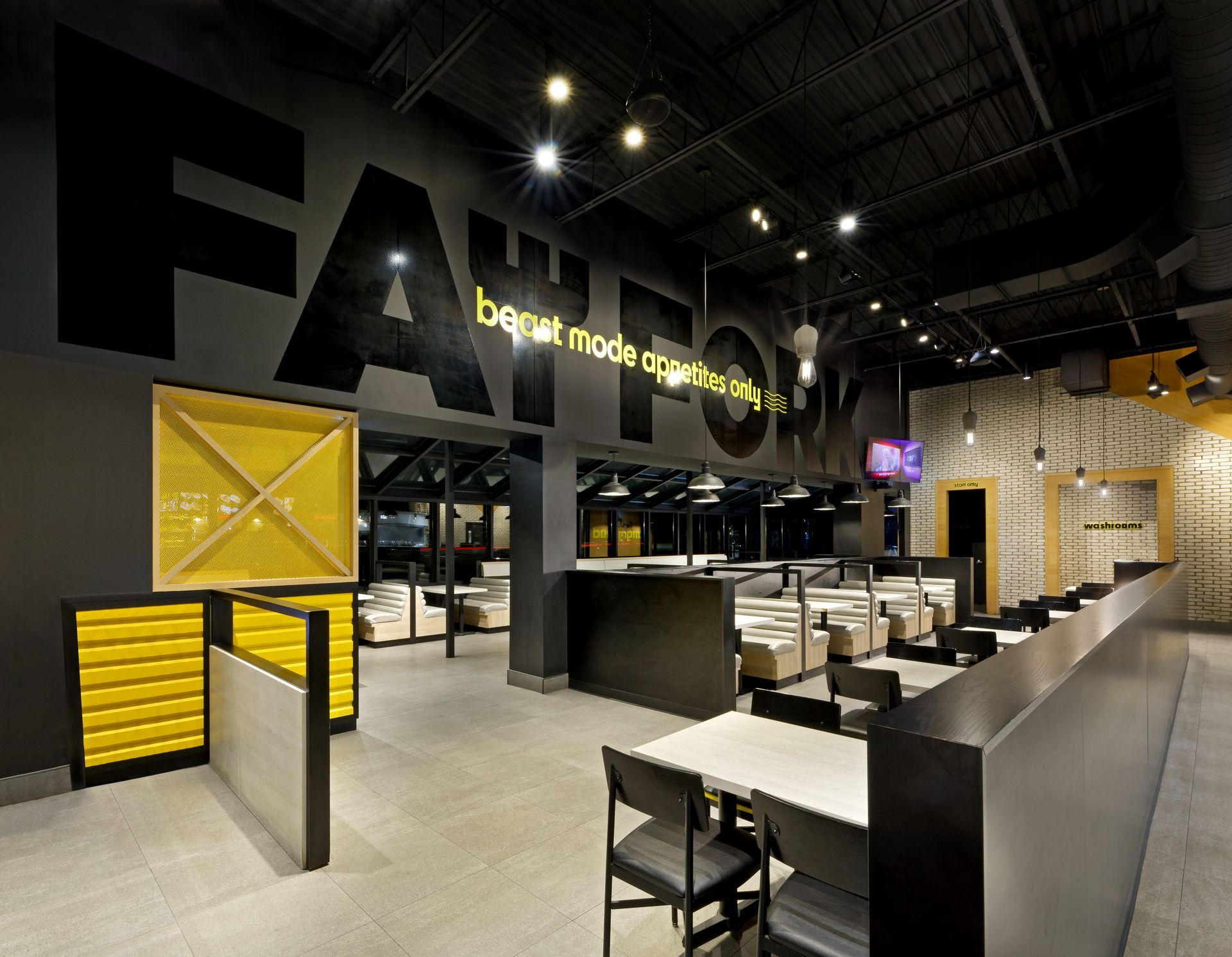 Modern fast-food restaurant interior with black, yellow, and white decor and empty tables