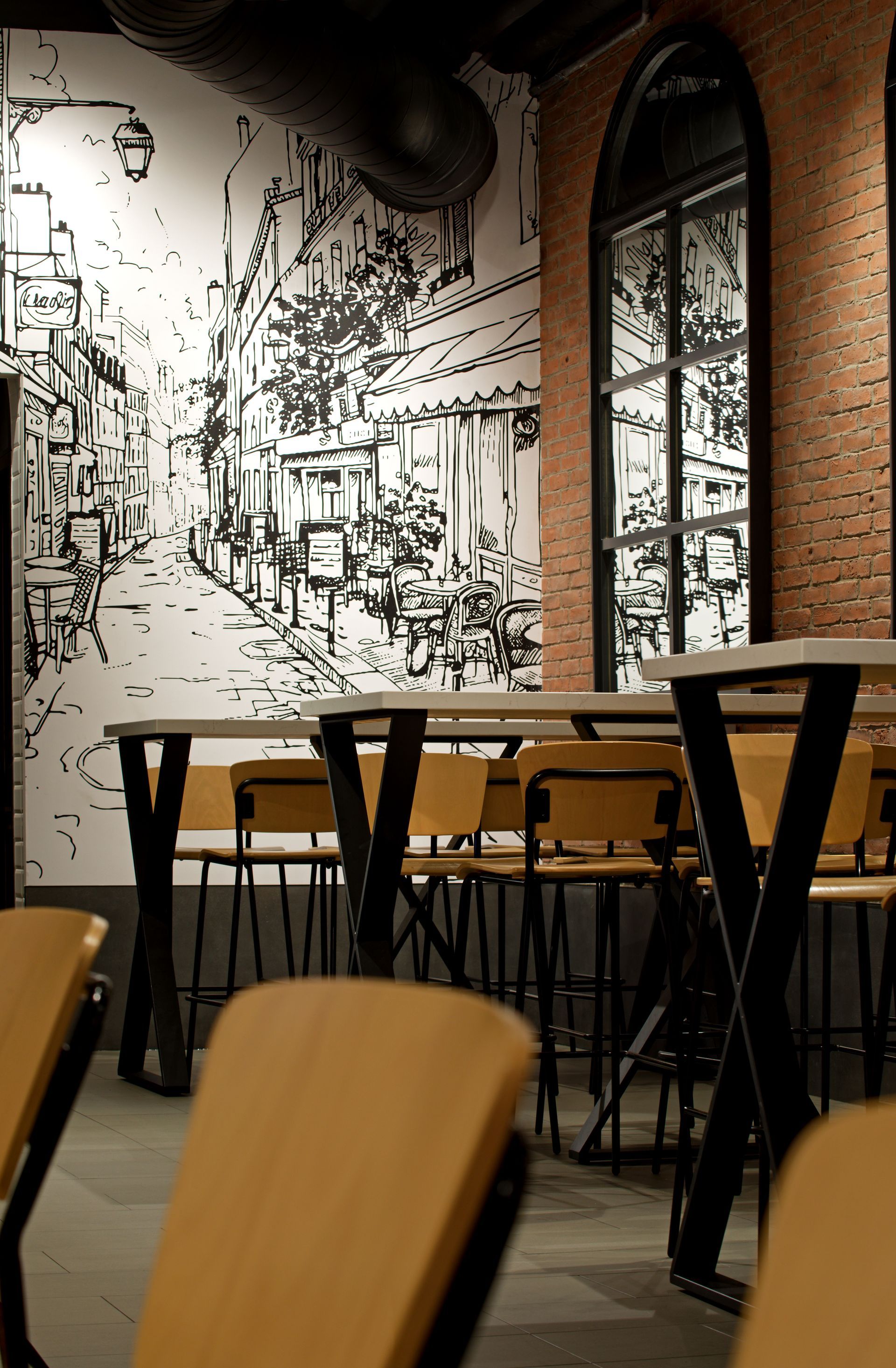 A room with tables and chairs and a mural on the wall