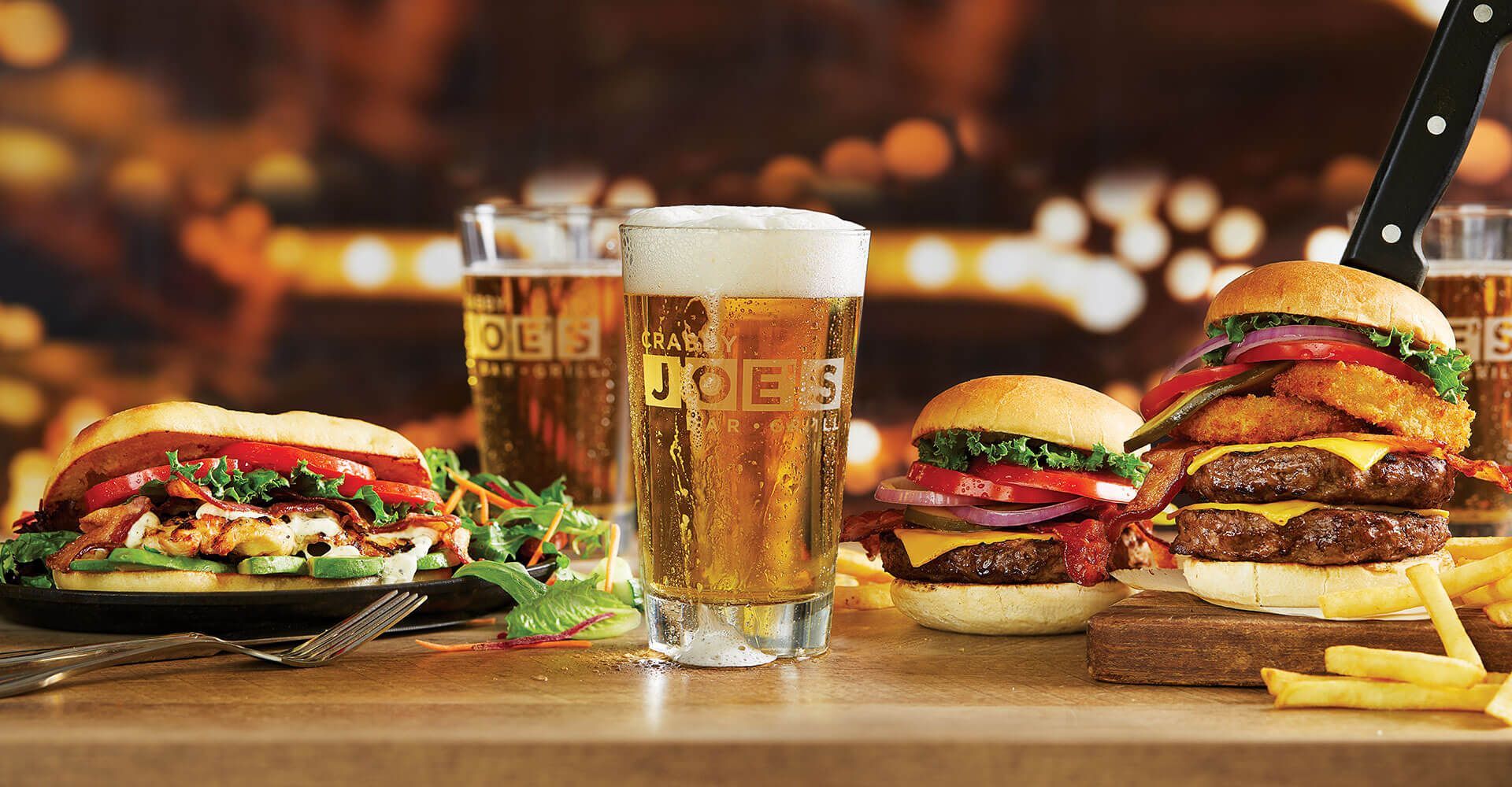 A table topped with hamburgers and a glass of beer.