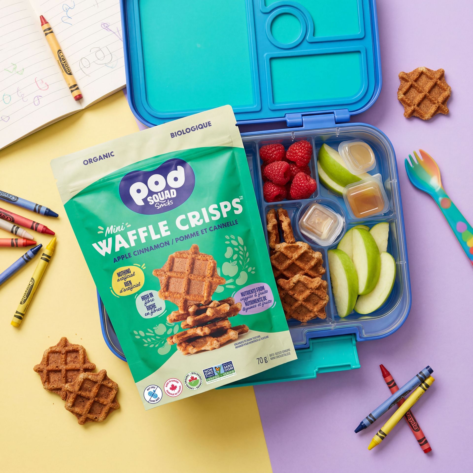 Lunchbox with snack foods, waffle crisps, fruit, and veggies on a bright classroom-style background