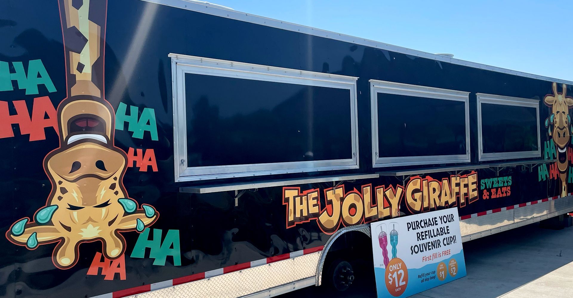A black bus with a giraffe on the side is parked on the side of the road.