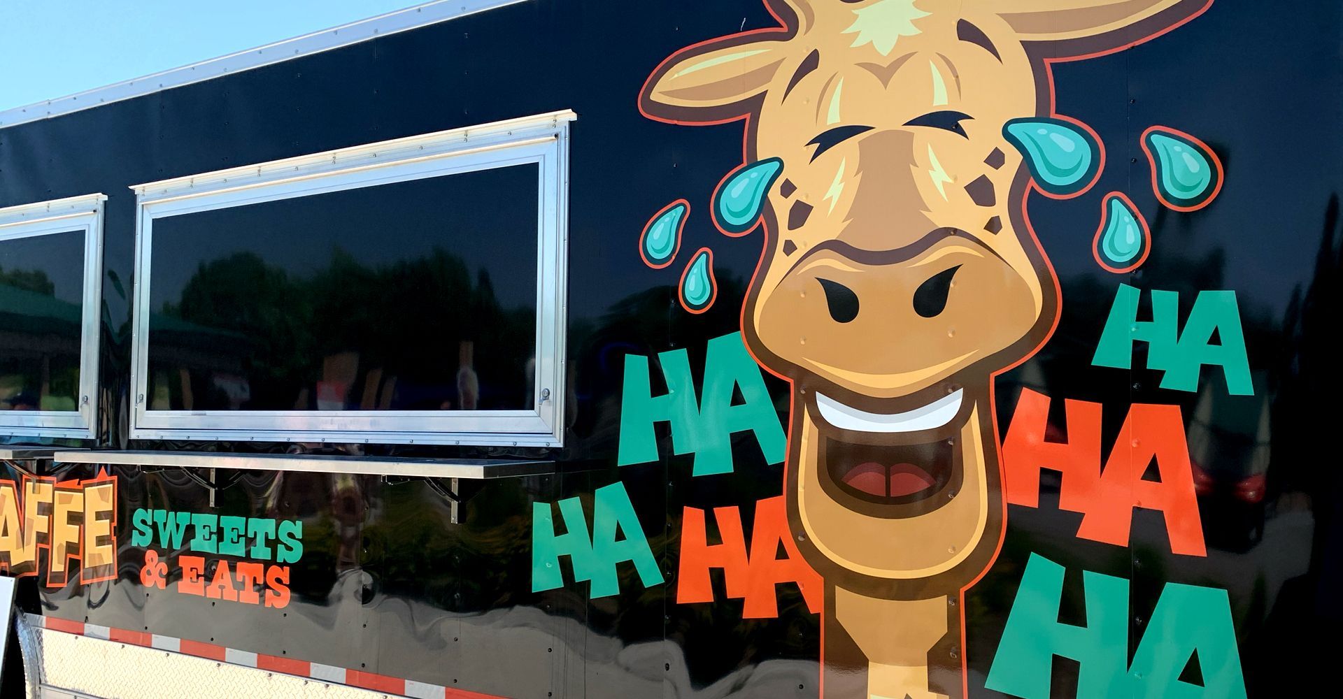 A giraffe is crying and laughing on the side of a truck.