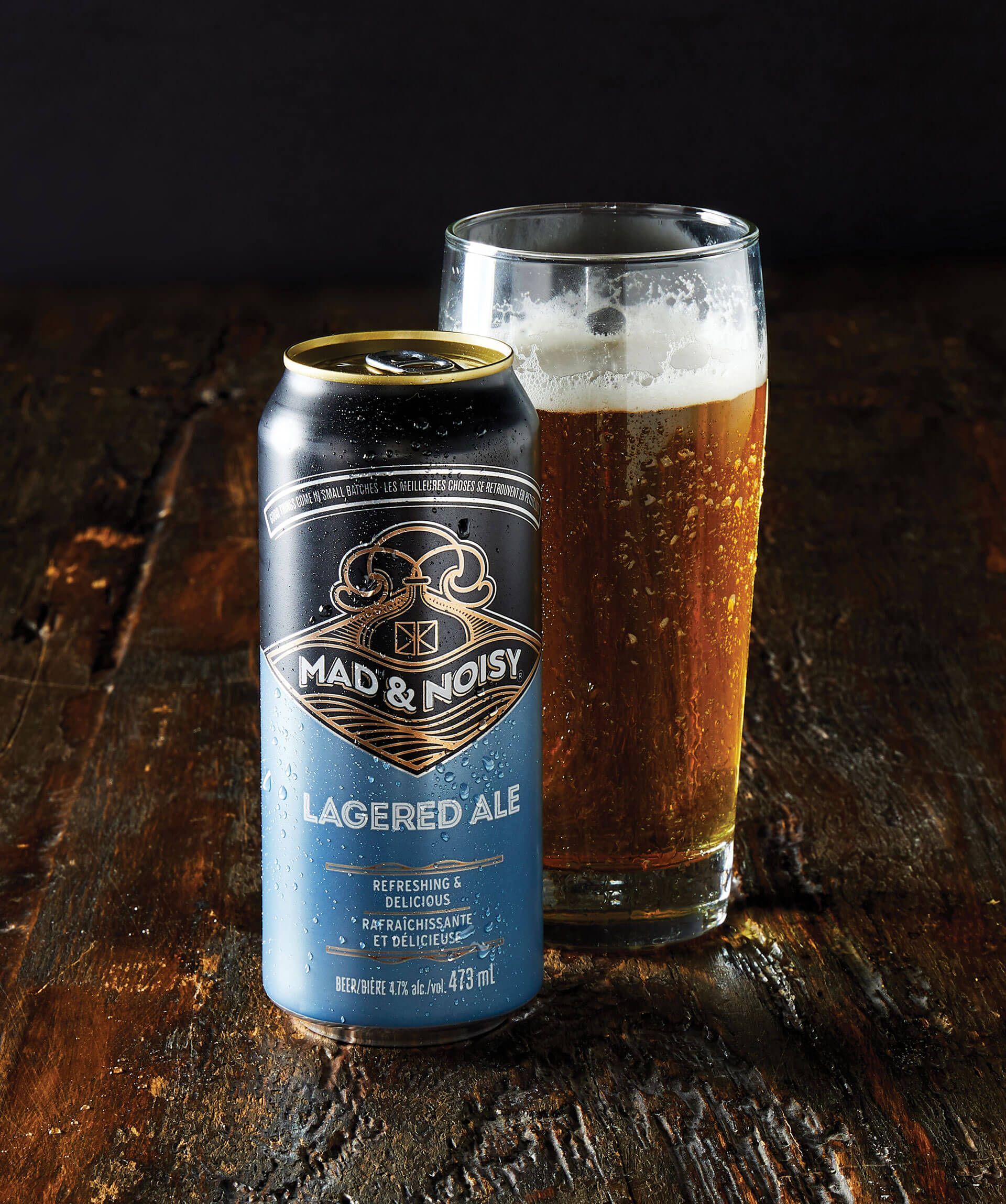 Blue can and pint of amber beer on a rustic wooden table