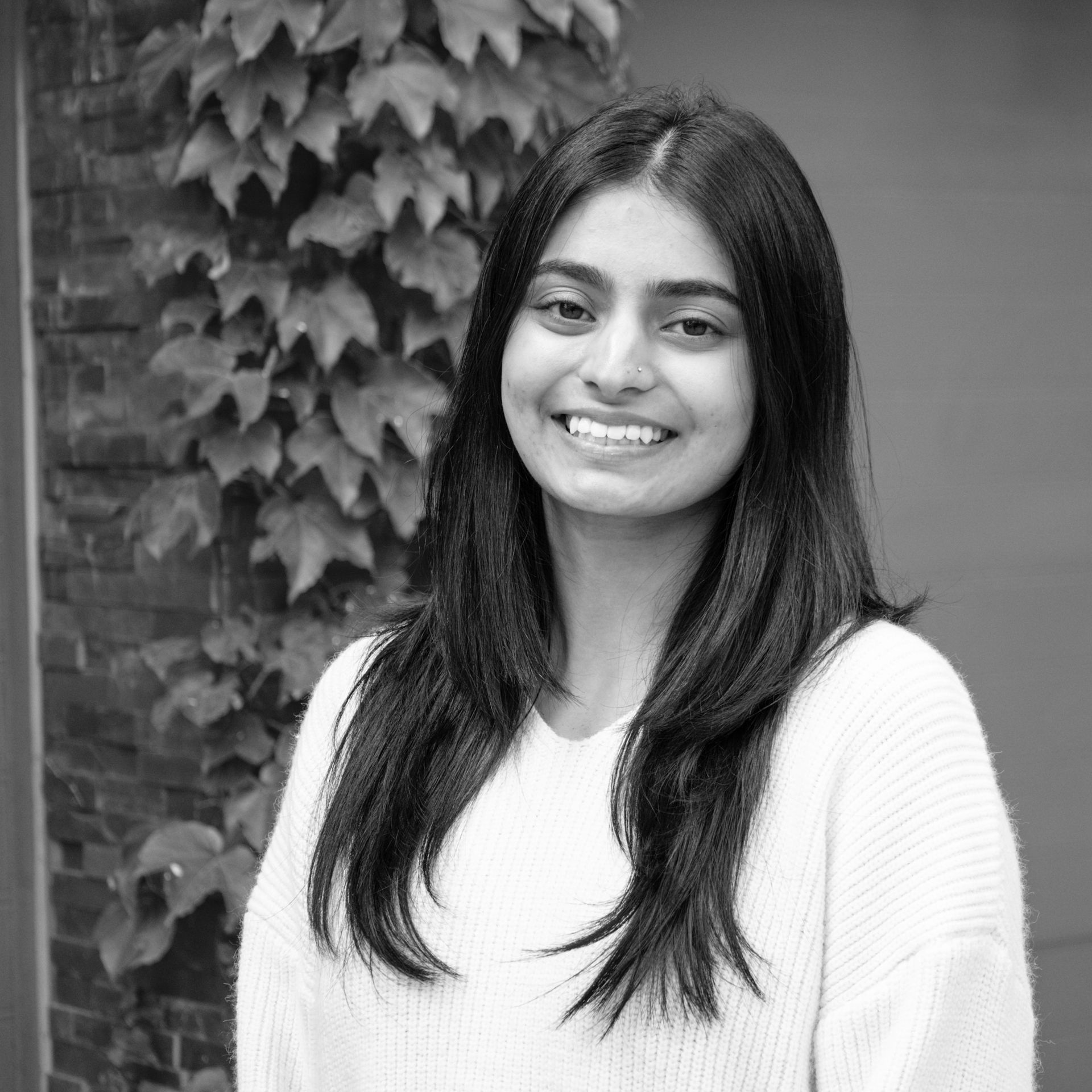 A woman in a white sweater is smiling in a black and white photo.