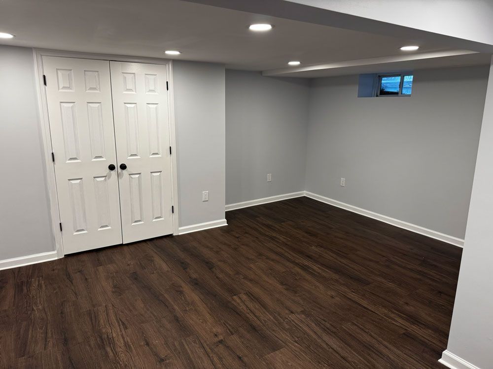 Finished basement with dark wood-look flooring, white doors, gray walls, and recessed lighting.
