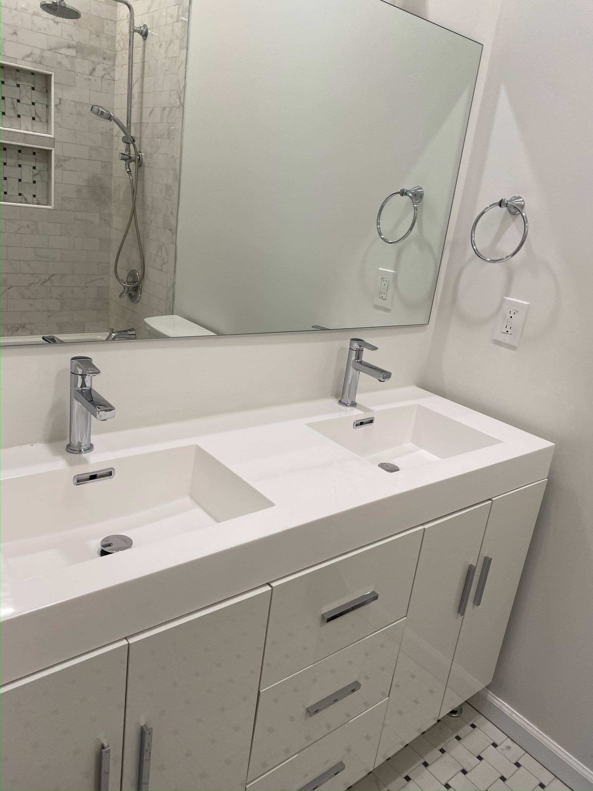 White double-sink vanity in a modern bathroom with a large mirror and chrome fixtures.
