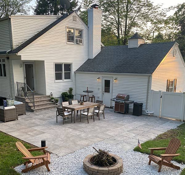 Backyard patio with dining table, Adirondack chairs, fire pit, and grill.