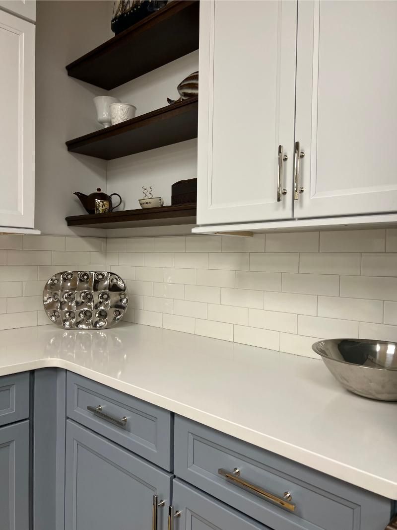 Kitchen with white and blue cabinets, white countertops, and open shelving with dishes.