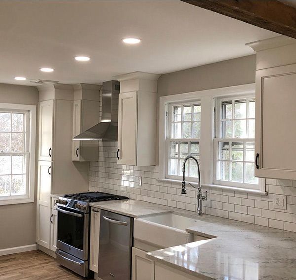 Modern kitchen with white cabinets, stainless steel appliances, and white tiled backsplash.