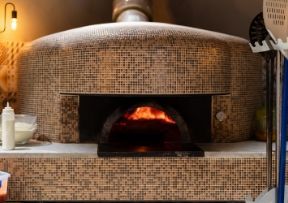 Brick pizza oven with flames visible in the opening.